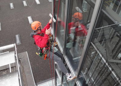 Fassadenkletterer reinigt Glasfront am Seil, Arbeit am hängenden Seil